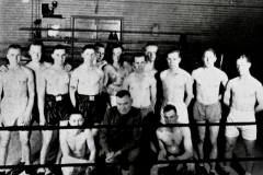 Boxing team posing in ring with their coach.